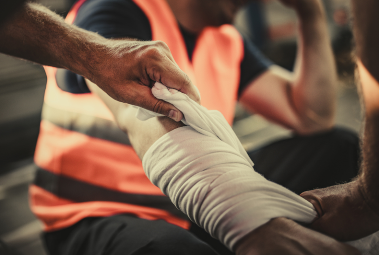 Image is of a construction worker with his arm bandaged, concept of common mistakes people make after a work injury