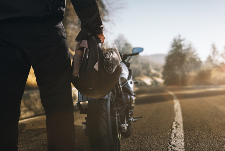 Image is of a partial view of a motorcyclist with motorcycle in the background, concept of hazards to avoid motorcycle accidents.