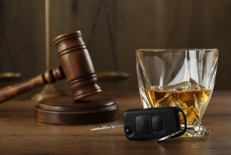 Image is of a glass of alcohol, a pair of car keys, and a judge's gavel behind them, concept of felony DUI