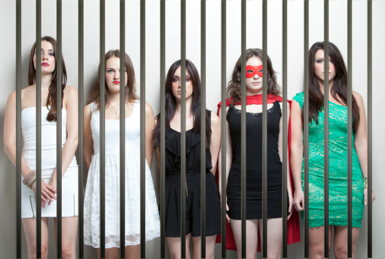 Image is of a group of women in a police line-up against a wall wearing costumes, concept of common crimes committed on Halloween