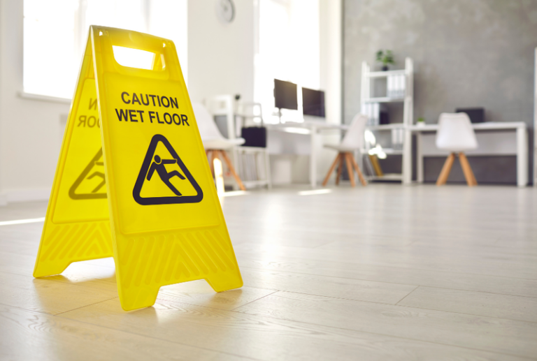 Image is of a yellow caution sign for a wet floor in an office, concept of premises liability cases