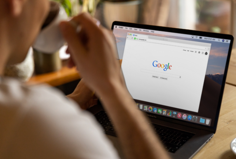 Image is of a man sipping a cup of espresso while on his laptop using Google search, concept of should you trust 'best car accident lawyer' search results