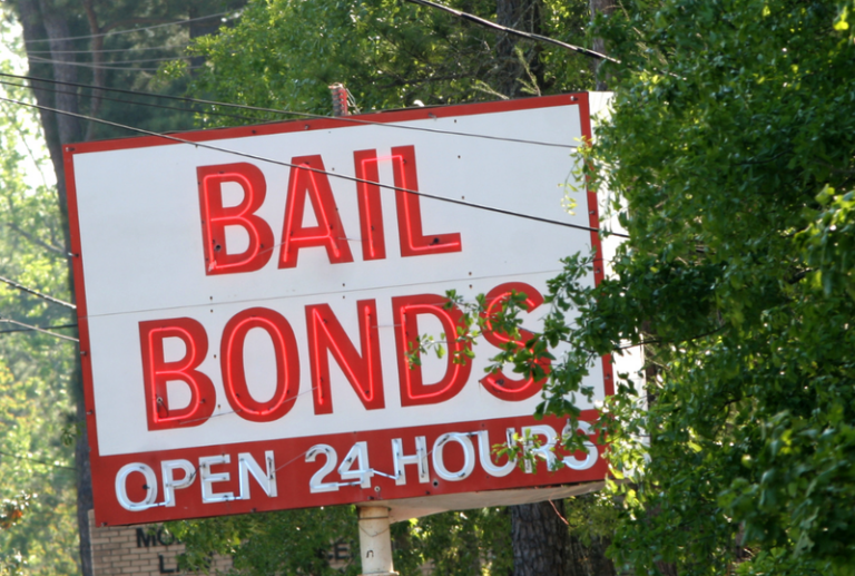 Image is of a white road sign with bright red letters that reads 'Bail Bonds Open 24 Hours', concept of bond hearings in South Carolina