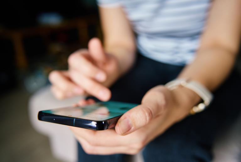 Image is of a closeup of someone on their smart phone looking at social media, concept of how social media can hurt your personal injury case