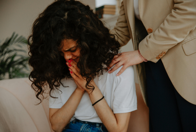Image is of a young woman upset and being comforted by another person, concept of suing for emotional distress after a car accident