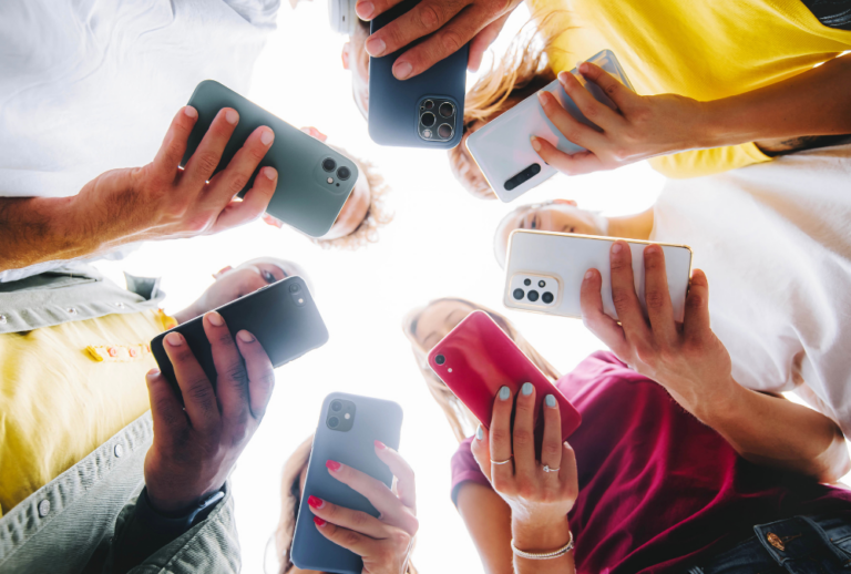 Image is of a group of teens looking down at their phones, concept of teen sexting laws in South Carolina