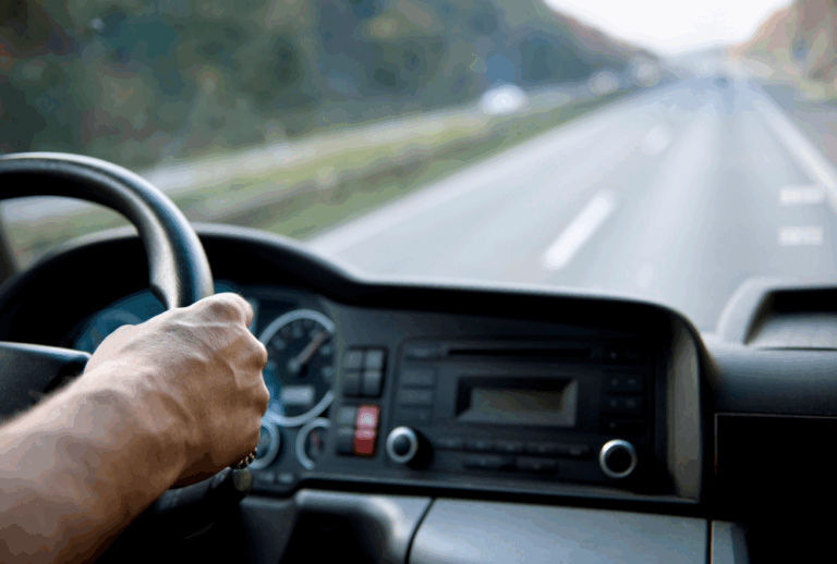 Image is of hands on the steering wheel of a truck while driving down the road, concept of losing CDL because of a DUI in South Carolina