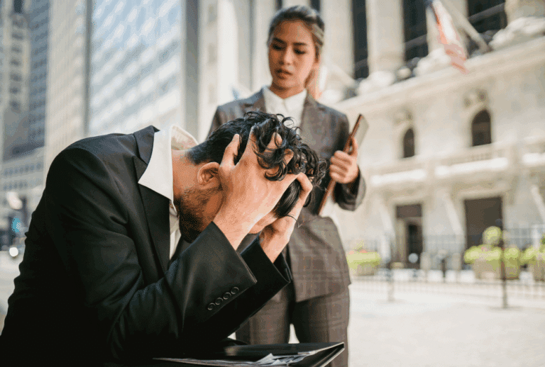 Image is of a young male professional with his head in his hands upset, while a female colleague is checking on him, concept of how a DUI charge in Aiken can affect your professional license