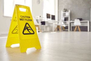 Image is of an office with a tile floor and a caution sign that says 'wet floor', concept of common hazards that lead to premises liability claims in Aiken