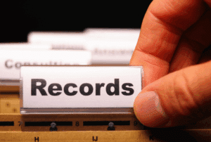 Image is of a closeup of a person's hand on a file folder that reads 'records' in a filing cabinet, concept of how long a n Aiken DUI stays on your record