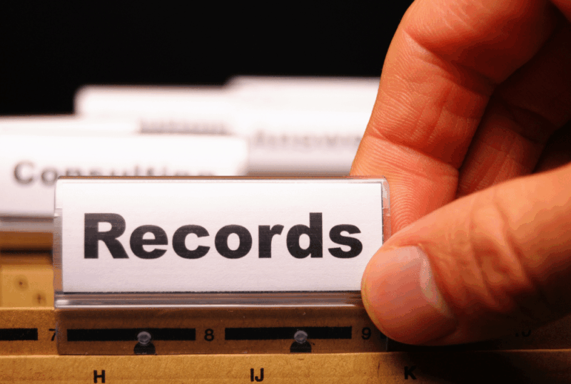 Image is of a closeup of a person's hand on a file folder that reads 'records' in a filing cabinet, concept of how long a n Aiken DUI stays on your record