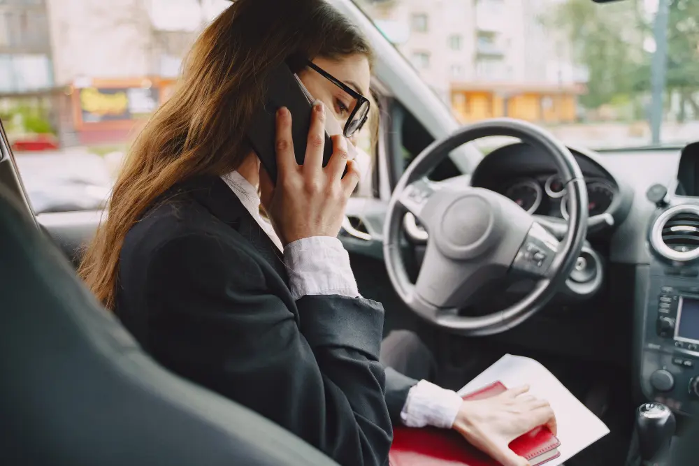 A woman sitting in her car making an emergency phone call