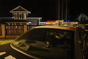 Image is of a police car outside of a house, concept of what happens after a domestic violence arrest in Aiken