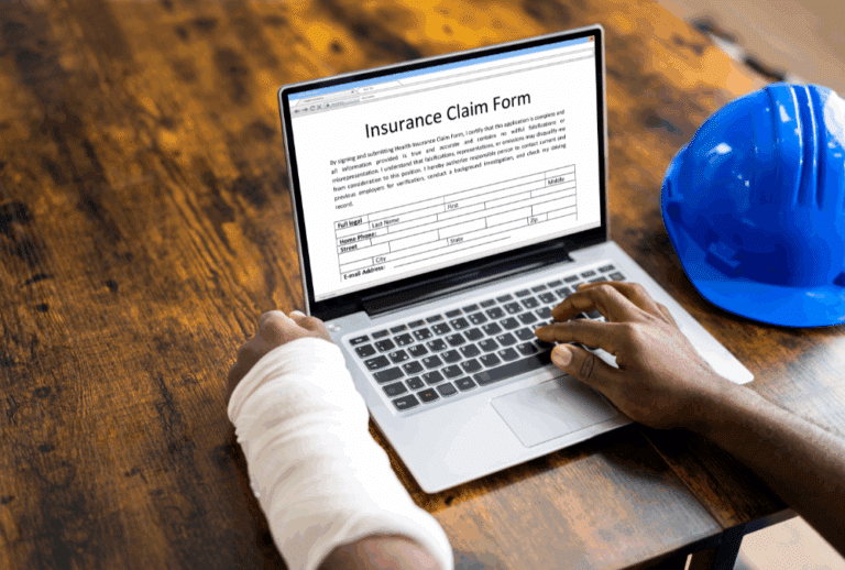 Image is of someone with an injured arm on the computer and filling out a workers' compensation form online, concept of how long to report a workplace injury in Aiken