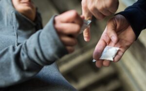 Close up of hands exchanging packets of drugs showing trafficking opioids in Aiken.