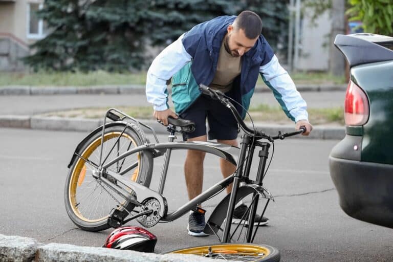 Cyclist inspecting damaged bicycle after a bike accident in Aiken.