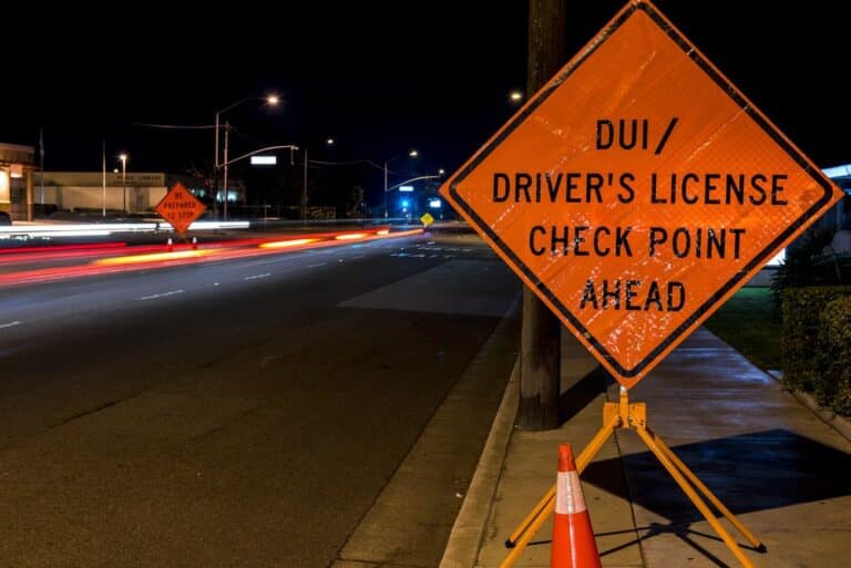 Image is of a DUI checkpoint warning sign on a city road at night concept of DUI checkpoint in Aiken