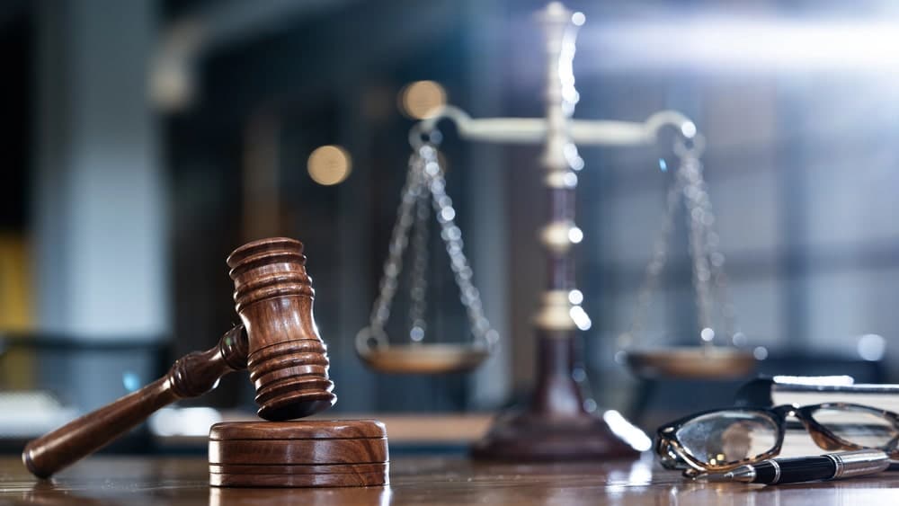 Image shows a gavel and scales of justice on a desk, symbolizing legal process and attorney representation