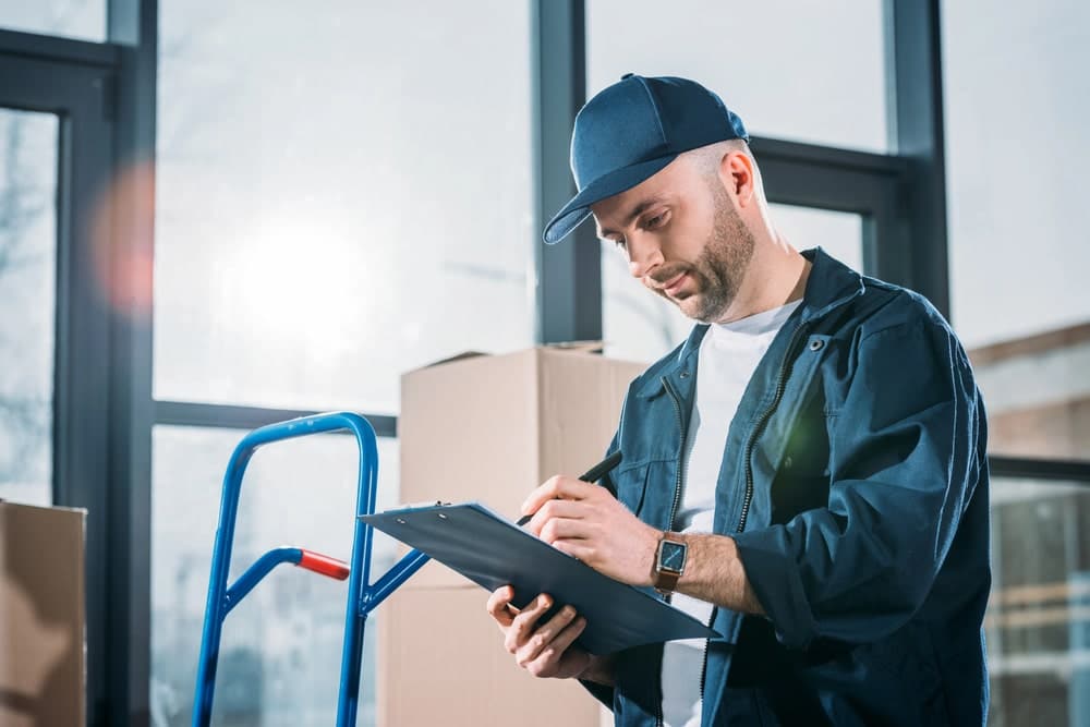 Image shows a worker taking notes on a clipboard during an inspection, concept of liability review in truck accident claim