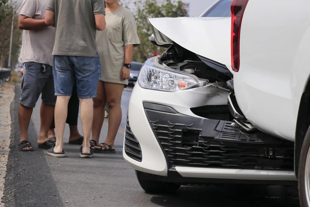 Image shows two cars damaged in a rear-end accident with people discussing the crash, concept of medical bills after a car crash in SC.