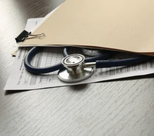 Image shows a stethoscope resting on medical paperwork and a folder, concept of medical bills after a motorcycle crash
