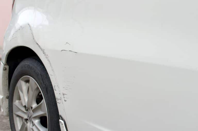 Image is of light scratches and scuff marks on a car door, concept of minor vehicle damage and when to consider a lawyer after a minor car accident