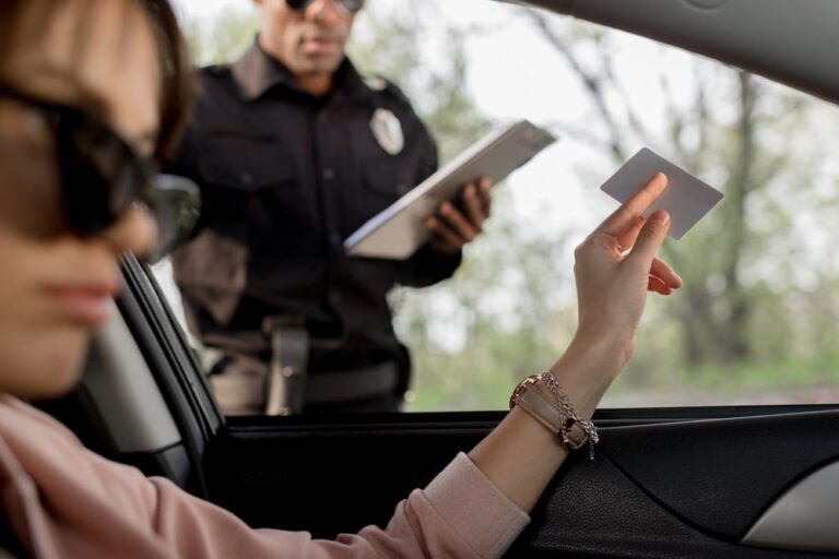Image shows a police officer speaking with a driver who is handing over identification during a roadside stop, representing how license suspension after DUI can begin immediately after a refusal.