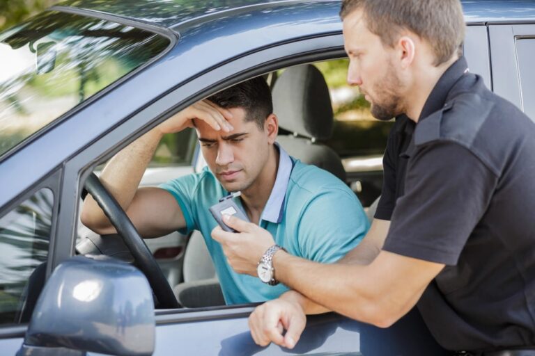 Image is of a police officer conducting a breath test during a traffic stop, showing how repeat DUI offenses are investigated and enforced