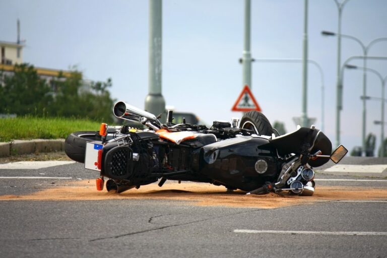 Image is of a motorcycle overturned on a public road after a collision, illustrating common crash scenarios that lead to serious injuries in motorcycle accidents.