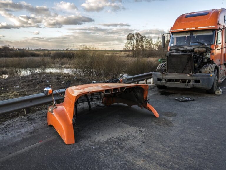 Image is of a heavily damaged semi truck with its front panel detached on a rural road, illustrating the violent impacts that often occur in truck accidents in SC and lead to serious injuries.