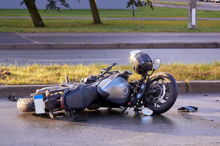 Image is of a fallen motorcycle on a roadway after a collision, concept of documenting crash scenes for a motorcycle accident claim