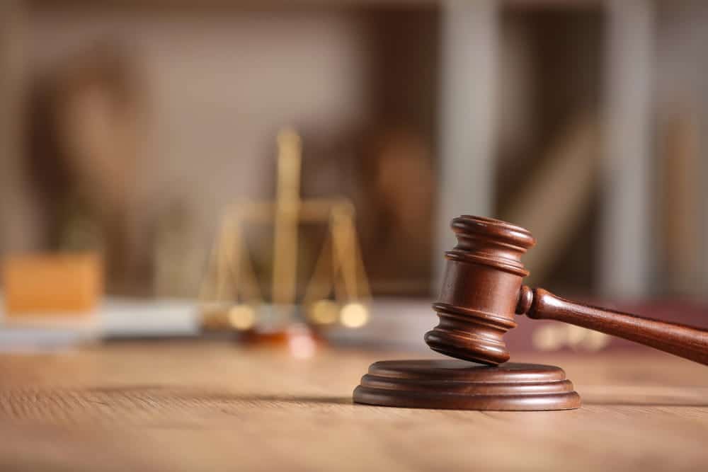 Image is of a judge’s gavel resting on a desk with justice scales in the background, concept of legal decisions involved in a motorcycle accident claim