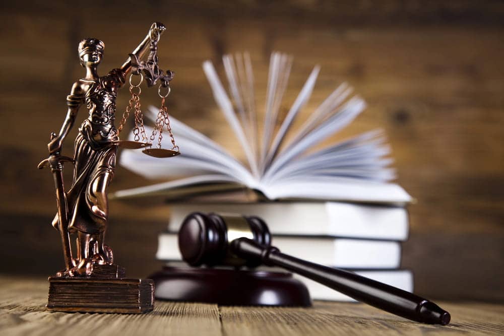 Image is of a Lady Justice statue with law books and a gavel, representing the legal process involved when a person misses DUI court in Aiken.