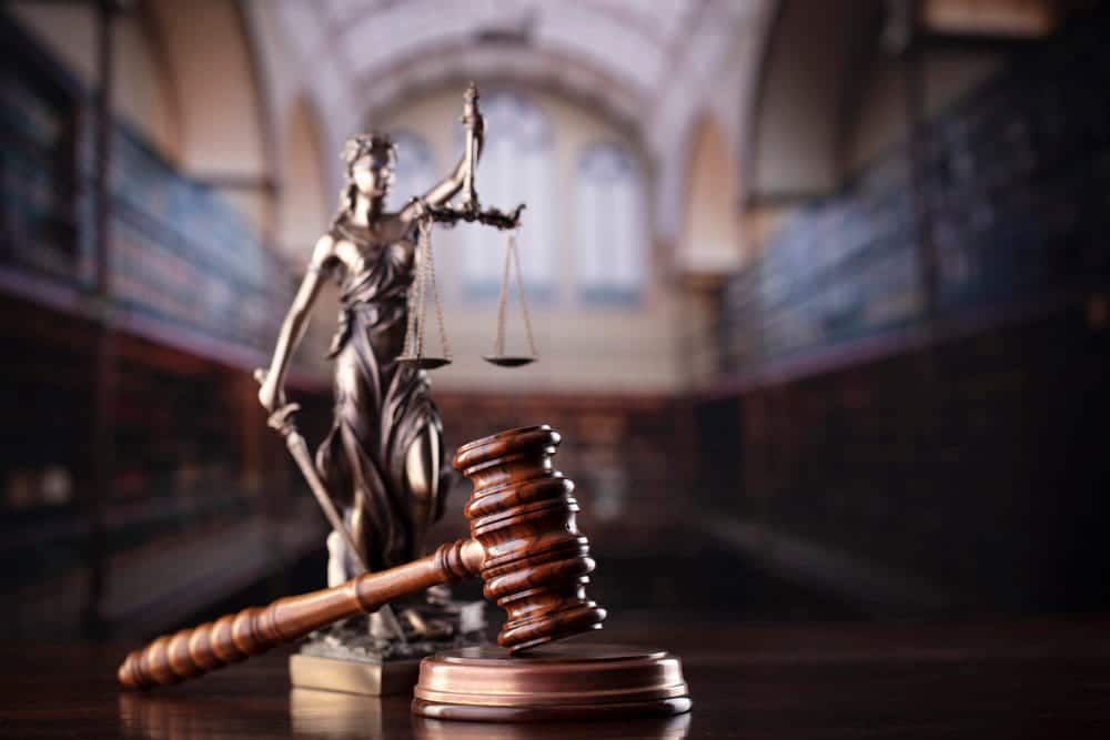 Image is of a courtroom scene with Lady Justice and a judge gavel, illustrating courtroom consequences related to missing DUI court in Aiken.