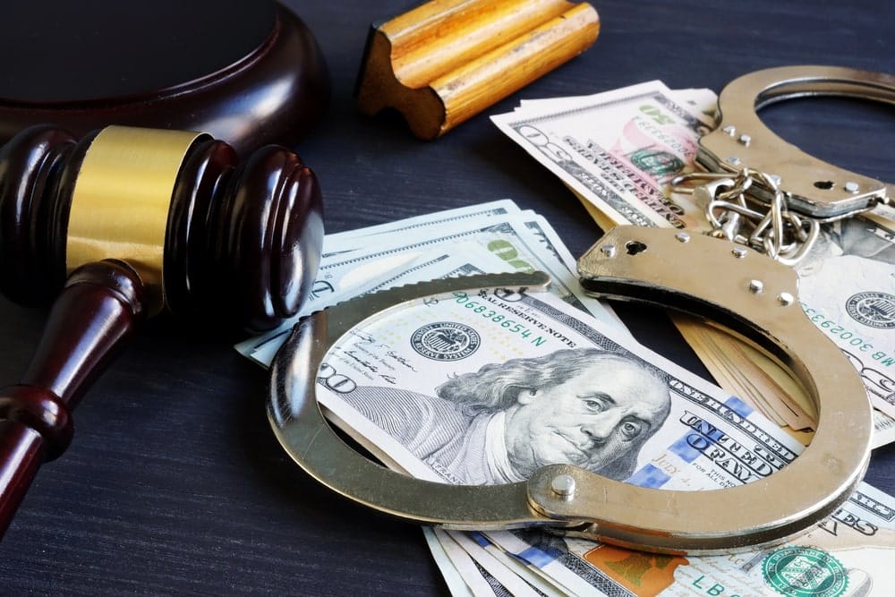 Image is of handcuffs and money beside a gavel, representing penalties and legal consequences in DV cases in SC