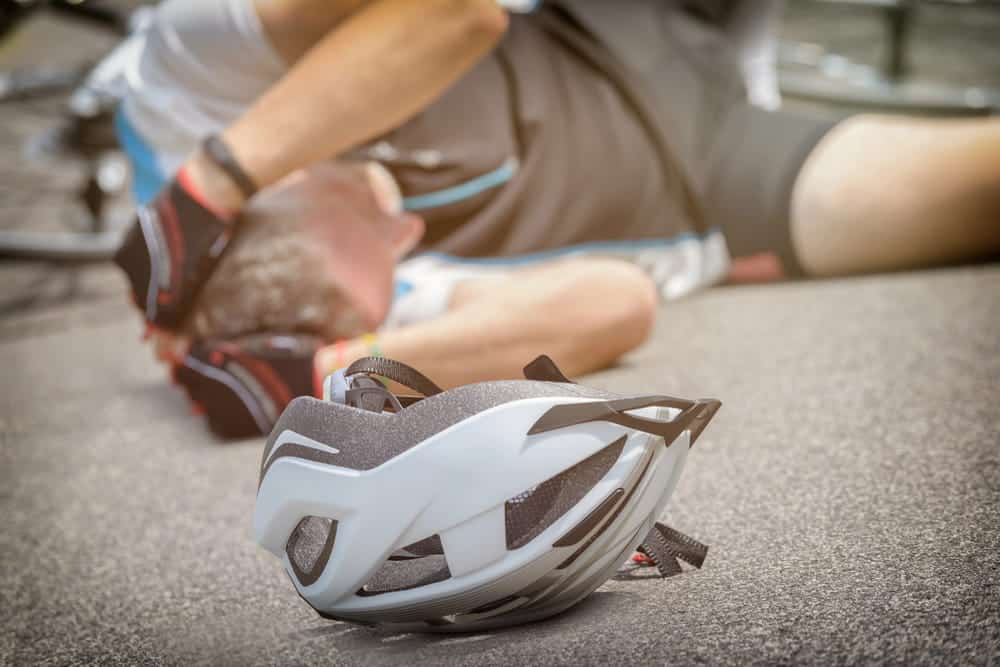 Image shows a bicycle helmet lying on the pavement after a fall, representing head injury risks commonly seen in bike accidents