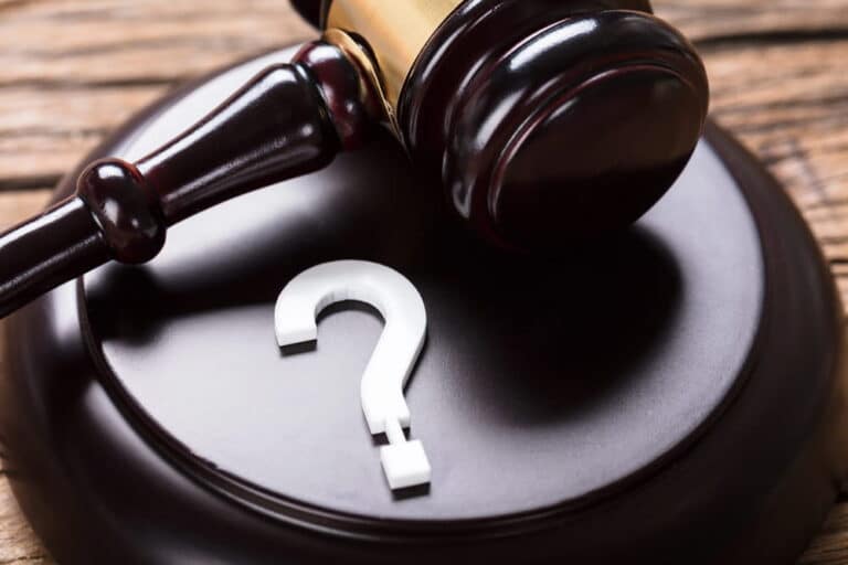Image is of a courtroom gavel beside a question mark, symbolizing legal uncertainty and how to sue a trucking company after a serious truck crash.