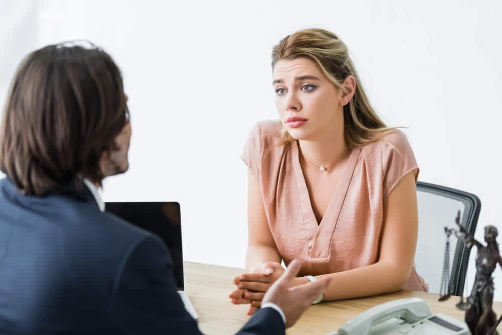 Image is of a woman discussing her case with a lawyer in an office, representing concerns about false domestic violence allegations