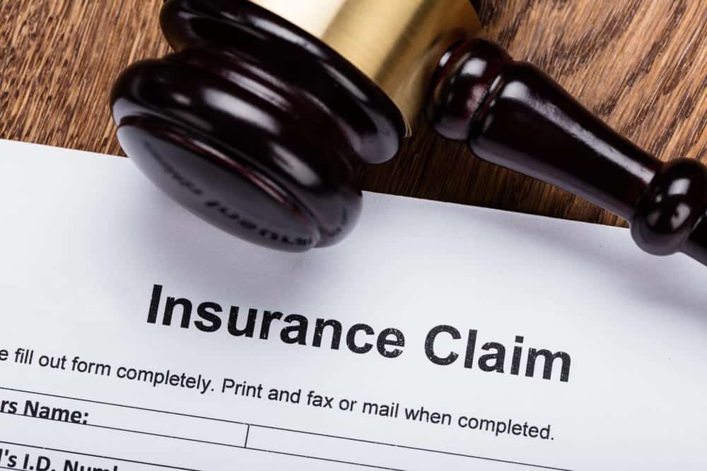 Image is of an insurance claim form with a gavel resting on top, concept of legal action required to file a car crash claim on time.