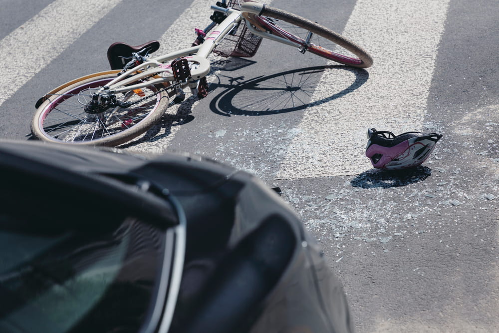 Image is of a damaged bicycle and helmet on the road after a collision, representing a bicycle accident claim following a crash in South Carolina.