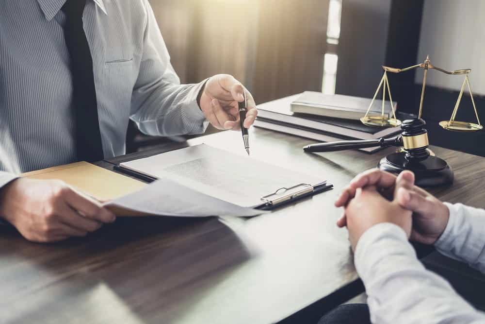 Image is of a lawyer reviewing documents with a client at a desk, concept of legal guidance after a drug arrest in Aiken.