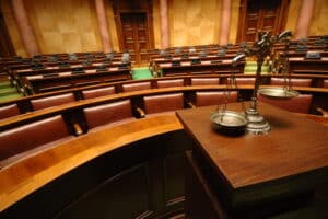 Image is of an empty courtroom with scales of justice displayed in front, representing legal proceedings after a drug arrest in Aiken.