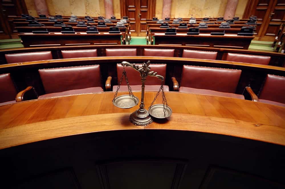 Image is of a courtroom with scales of justice placed in front, representing legal process after a motorcycle crash