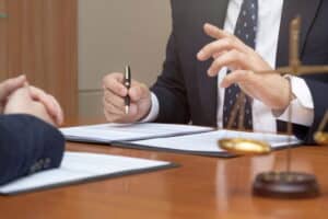 Image is of a lawyer discussing a case with a client at a desk, concept of drug charges and legal consultation