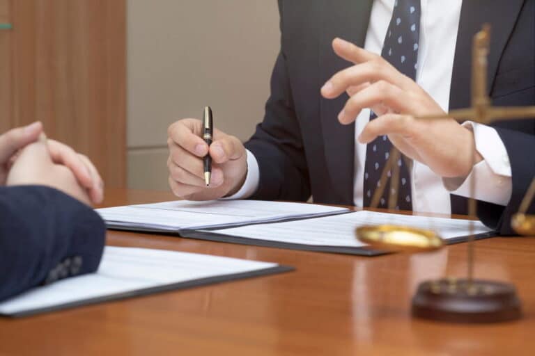Image is of a lawyer discussing a case with a client at a desk, concept of drug charges and legal consultation