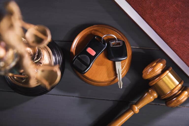 Image is of a judge’s gavel placed near car keys and a legal book, representing a DUI bond hearing process and court decision context
