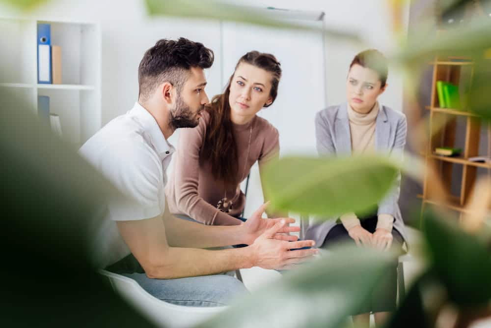 Image is of individuals participating in a counseling discussion with a support group, concept of treatment and recovery programs connected to a drug court appearance in Aiken.