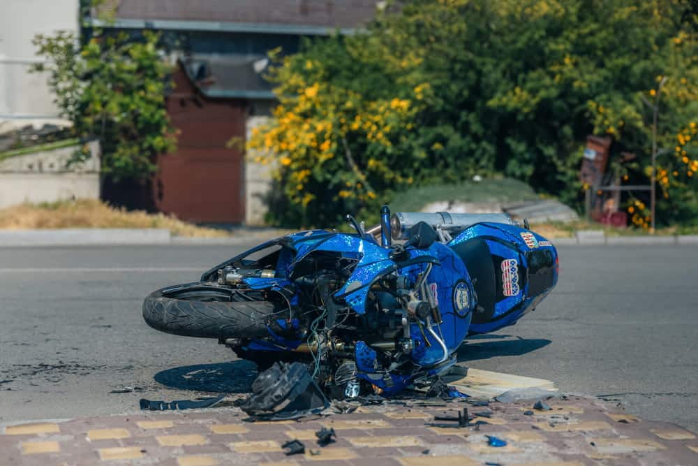Image is of a damaged motorcycle lying on the road after a crash, illustrating motorcycle accident insurance and accident-related damage assessment