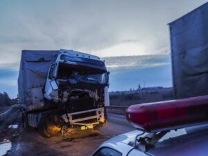 Image is of a damaged semi truck after a highway collision, showing the aftermath of a truck accident and evidence at the scene