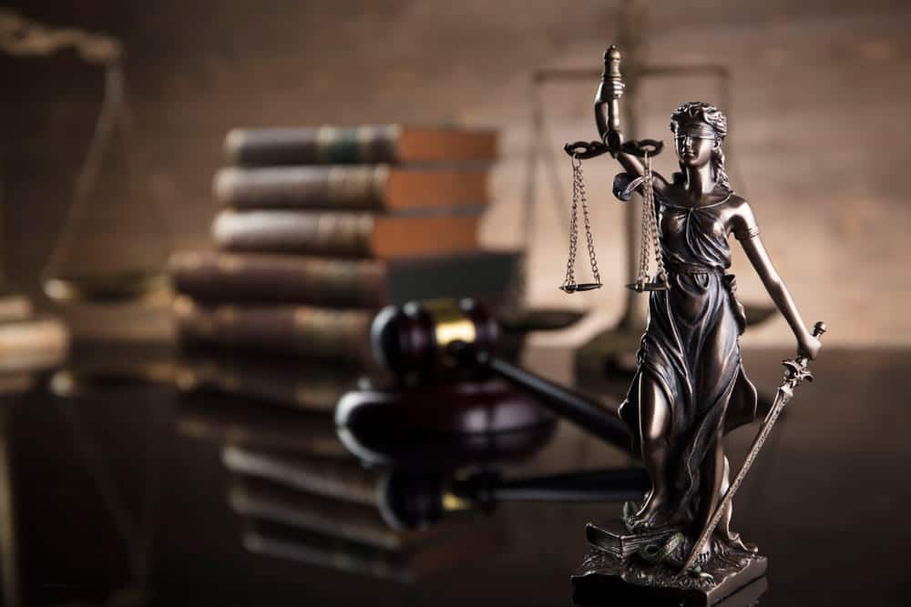 Image is of Lady Justice statue with legal books and gavel, symbolizing court enforcement of a protective order